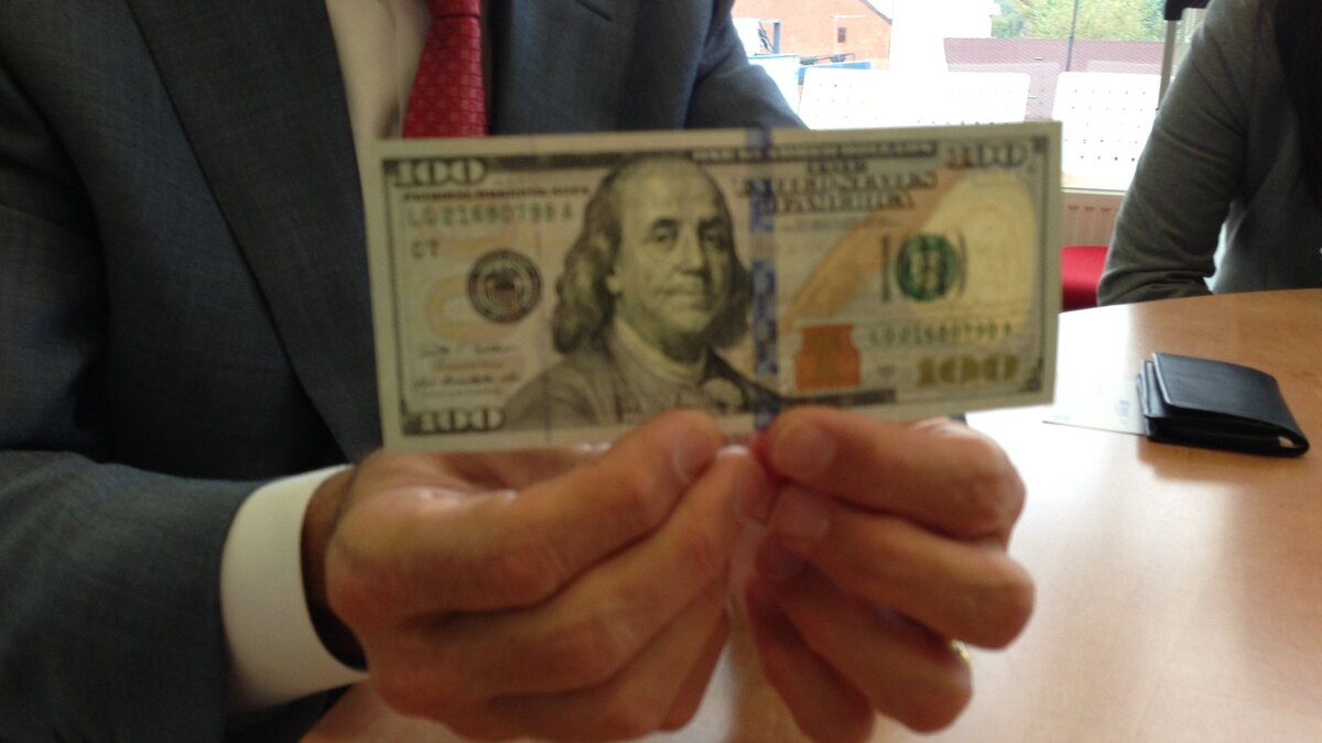    Заместитель начальника отдела банковских операций и платежных систем ФРС Майкл Ламберт демонстрирует новую купюру© РИА Новости/Аврора