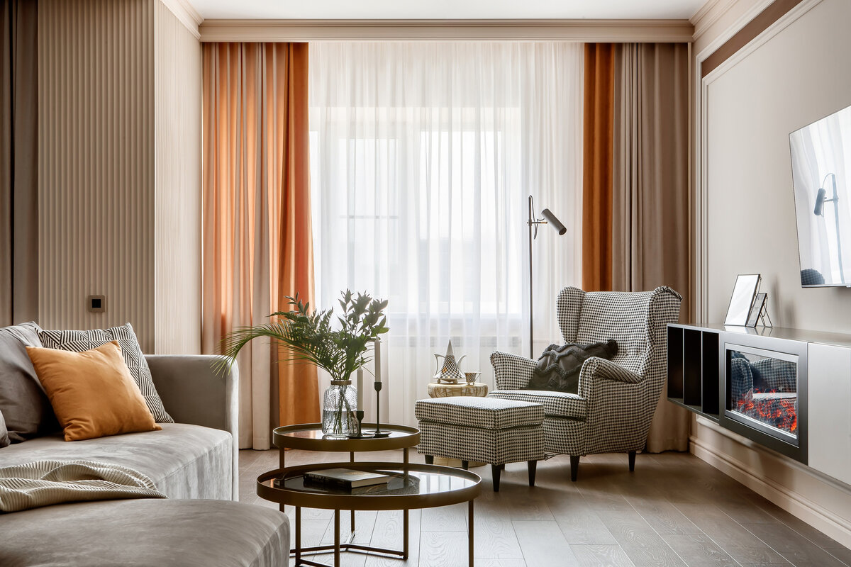 Гостиная с уютным декоративным камином. Здесь предусмотрено несколько зон для отдыха — большой диван и кресло с подставкой для ног