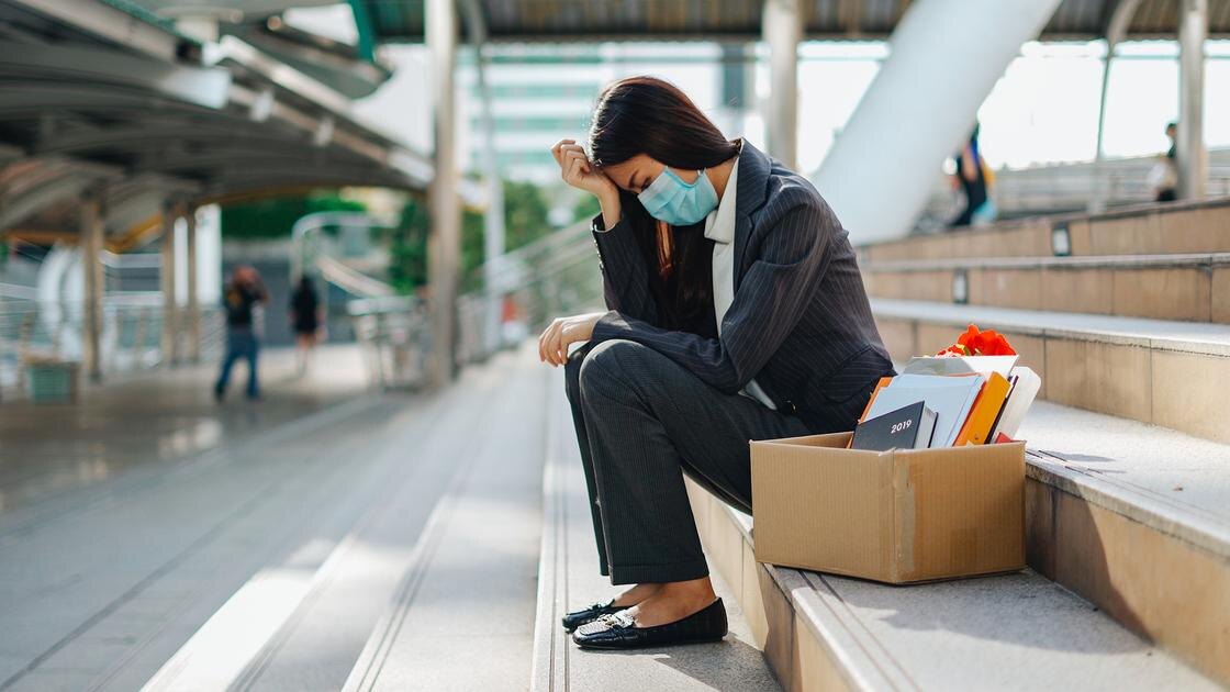    Женщина в маске сидит на лестнице с коробкой канцелярских принадлежностей:Kiattisak Choohnoo/EyeEm/Getty Images