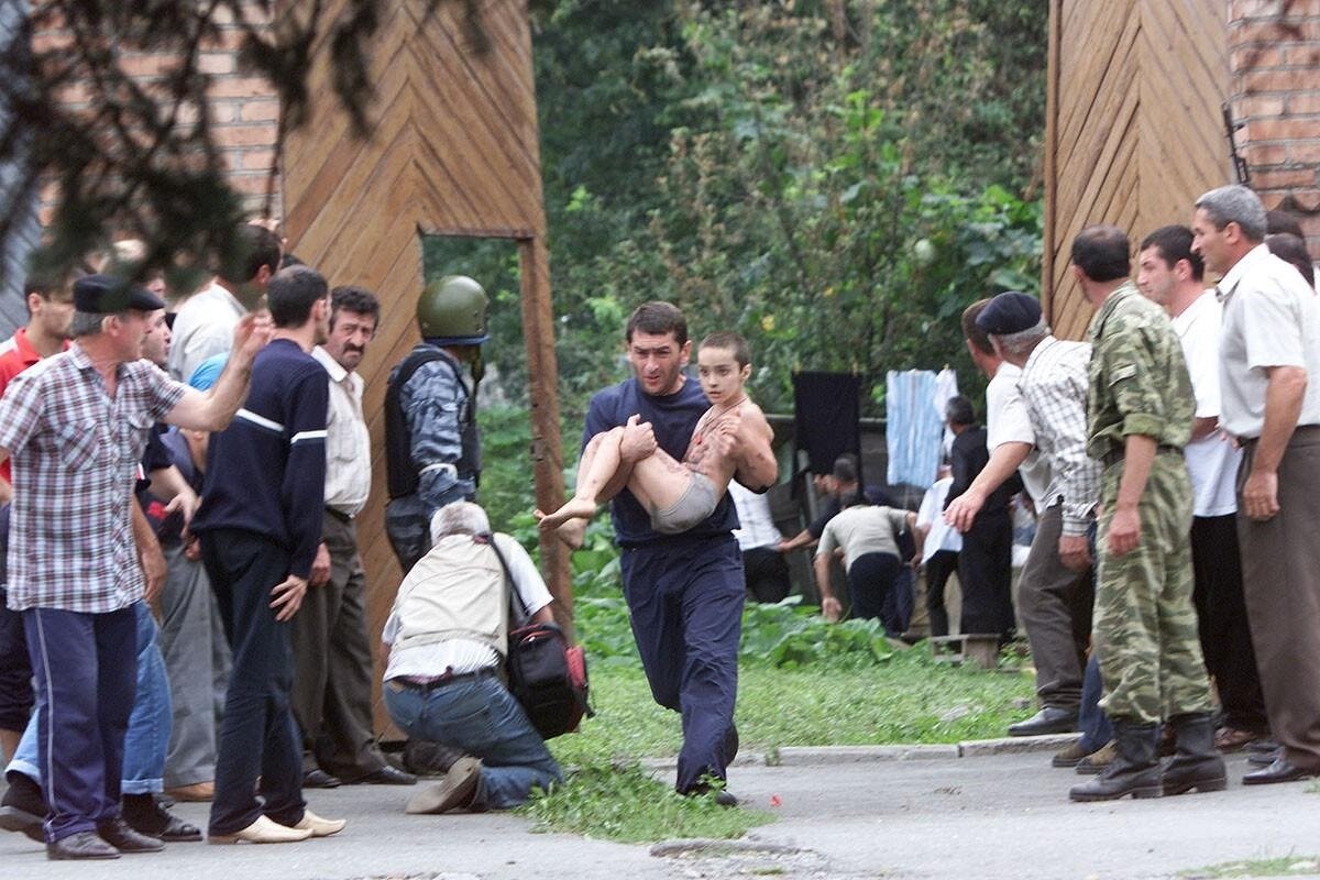 Мужчина на руках выносит ребенка из захваченной школы.