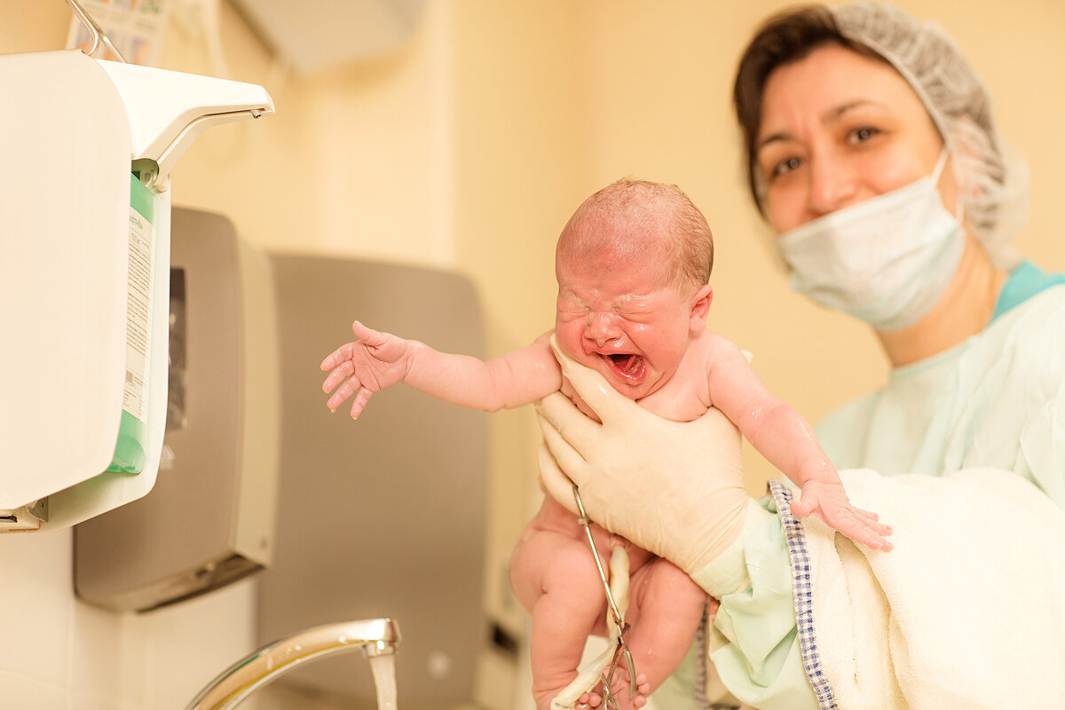 Ребенок мама роддом. Акушерка с новорожденным. Медицинская сестра и новорожденный. Младенец на руках у акушерки.