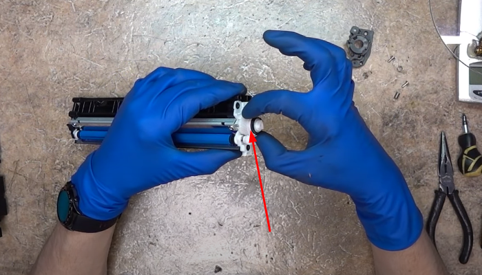 Фото 54. Вставляем кусочек плотного полиэтилена в промежуток между дозирующим лезвием и роликом подачи тонера (крупный план)