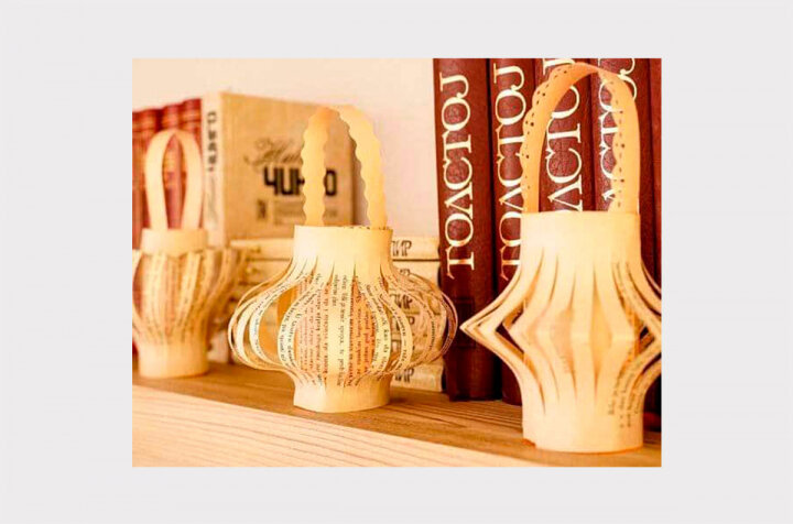 Фонарики
Вырвите 2 страницы из книги, ножницами подровняйте стороны отрыва.
Первую сверните в трубочку и закрепите края при помощи степлера или клея. Должен получиться цилиндр.
Вторую страницу сложите пополам по длинной стороне и сделайте надрезы через равные промежутки.
Деталь с прорезями прикрепите к цилиндру, чтобы верхние и нижние края были на расстоянии минимум 1 см и получилась объёмная «юбка».
Вырежьте полоску бумаги и приклейте её в качестве ручки. Вуаля, фонарик готов!