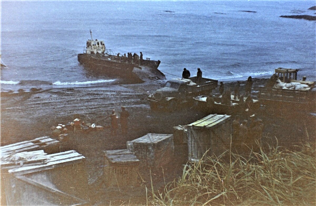 Разгрузка на перешейке "Ветровое" (Итуруп). Тот редкий случай, когда фотография сделана именно в том месте, и всего за пару часов до описываемых событий. На заднем плане видны камни, на одном из которых сидела баржа. Правда баржа не та. Моя стоит левее (виден маленький кусочек). Если идти влево, то там "Белые скалы", а если вправо, там уютный грот-ракушка.