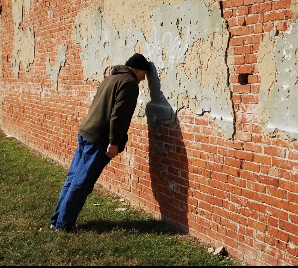 Бить головой стену. Головой об стену. Человек перед кирпичной стеной. Человек у стены. Человек уперся в стену.