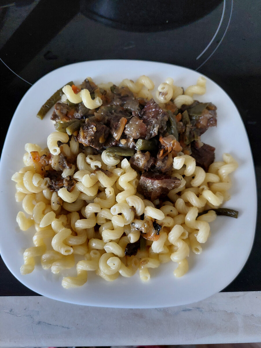 Это фото ужина в маленькой сервировочной тарелке. Тушеное мясо с овощами и макароны. Объем кажется не просто большой, а огромный.