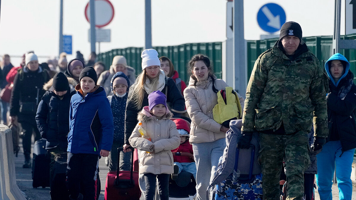 Украинские беженцы с польским пограничником 26 февраля на границе Польши. Фотограф — Czarek Sokolowski.