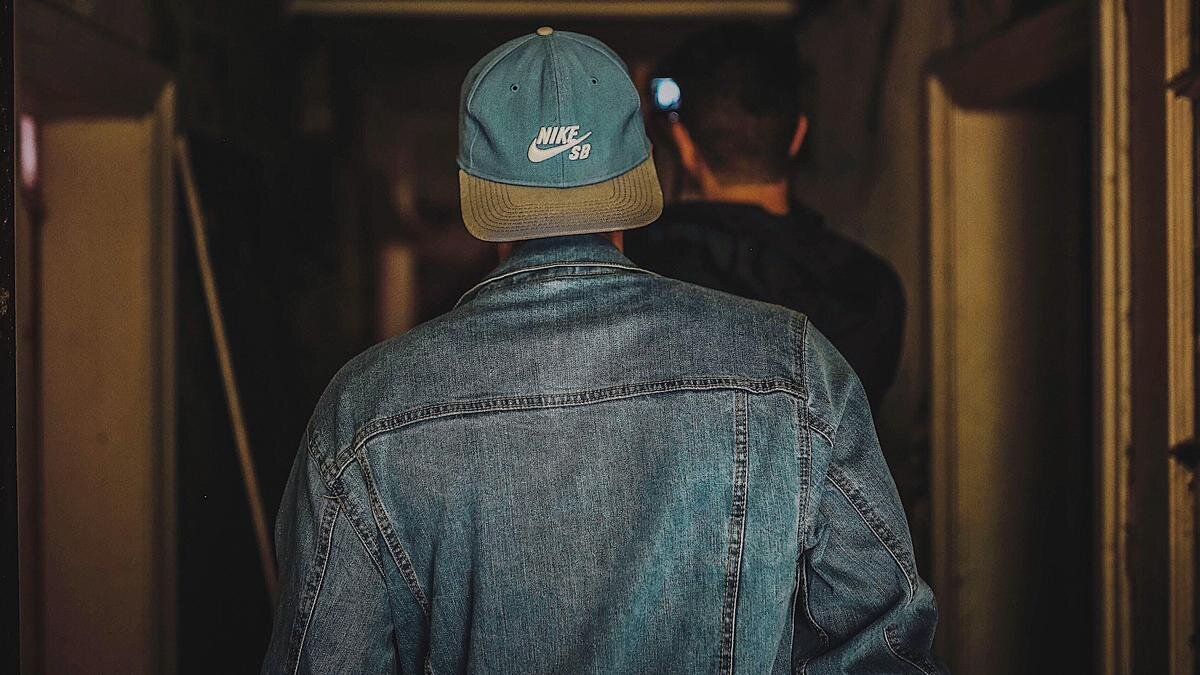    Парень в кепке и джинсовой куртке идет по коридору:pexels.com