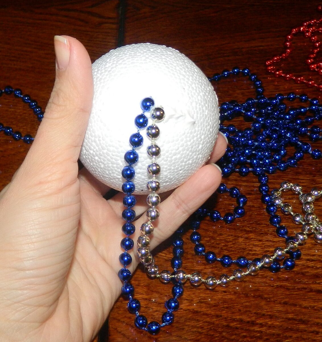 К синей цепочке присоединяется украшение серебристого цвета