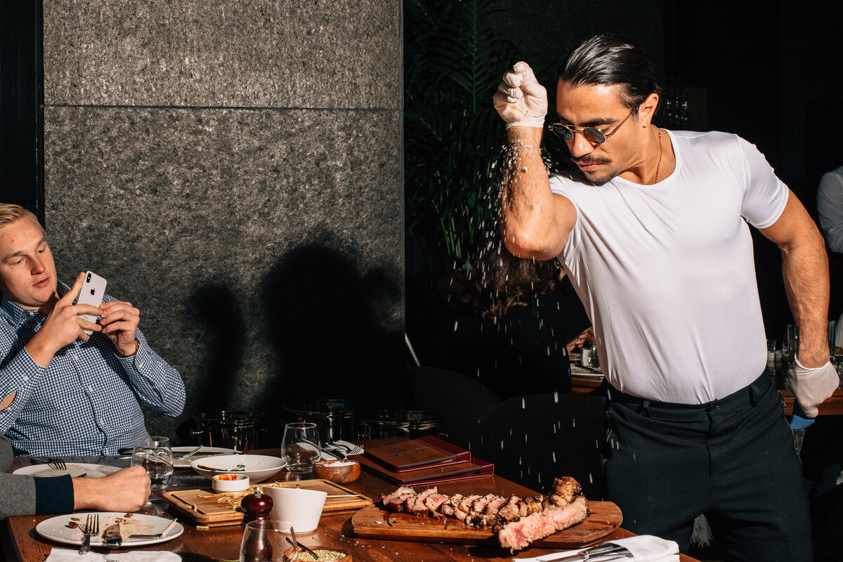 SaltBae солит стейк, а посетитель снимает видео, чтобы поделиться им в соцсетях