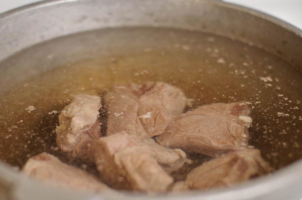 Дольше всего готовится мясо. С него и начнем. Мясо нужно вымыть, залить чистой холодной водой и поставить вариться. Если мясо с костями, то его нужно предварительно разрубить на куски. Филе лучше положить целиком. Важно! Мясо лучше заливать водой холодной для получения прозрачного бульона. Варить после закипания мясо необходимо на медленном огне, примерно два часа, время от времени снимая пенку. Если стремитесь к получению более прозрачного бульона, то лучше не забывать пенку снимать. Вместе с мясом нужно положить одну очищенную морковку и одну, хорошо вымытую и разрезанную пополам неочищенную луковицу. Место роста корешков нужно срезать. Они придадут особый вкус и золотистый цвет бульону. Соль добавлять в него его пока не нужно.