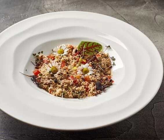 Ингредиенты на одну порцию:Томаты черри — 50гКускус отварной — 70гСельдерей черешковый — 20гЛук красный — 15гЗелень (кинза, мята, укроп, петрушка, зеленый лук) — 5гМасло конопляное — 20гКонопляные ядра — 5гСпособ приготовления:Чтобы приготовить вкусный кускус, нужно взять в соотношении 1:1 крупу и маринад от консервированных оливок. Жидкость довести до кипения и залить ей кускус. Накрыть крышкой и дать постоять 10 мин. После этого перемешать и можно использовать.Красный лук нарезать полукольцами, сельдерей тонкими пластинками, зелень мелко порубить, томаты черри разрезать пополам.Все компоненты смешать и заправить конопляным маслом.