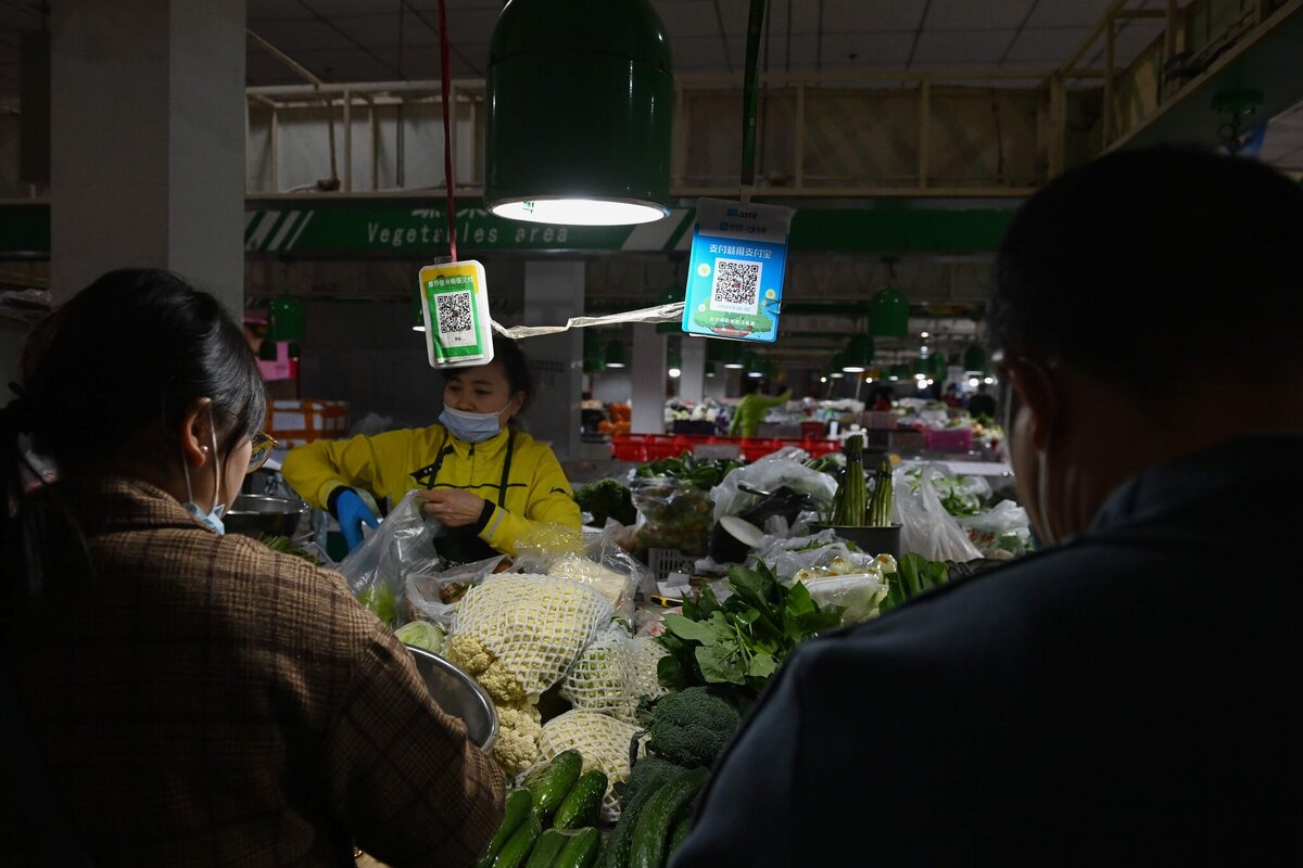 Покупатели ждали возле Alipay (справа) и QR-кодами оплаты WeChat на рынке в Пекине в октябре. Грег Бейкер / Agence France-Presse - Getty Images