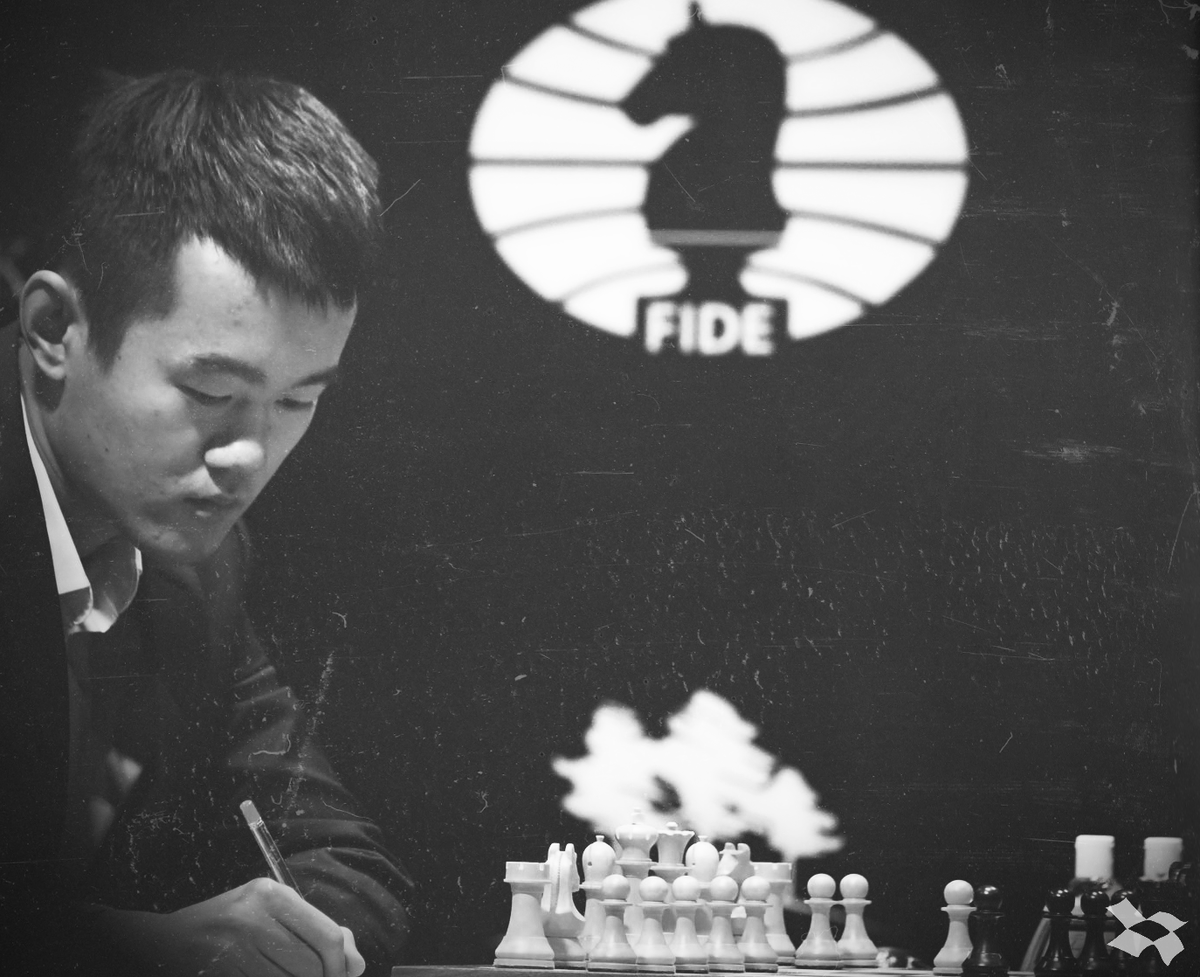 Дин Лижэнь - китайский шахматист, гроссмейстер. На фоне виднеется логотип ФИДЕ.