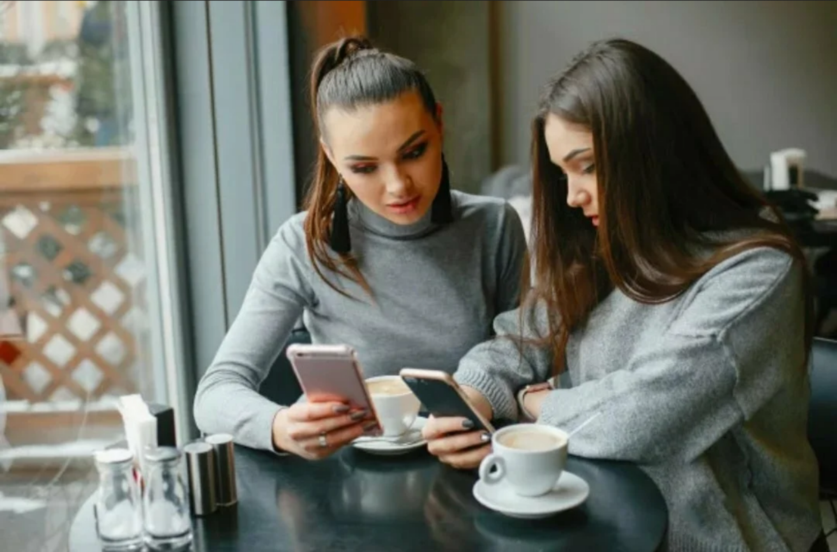 Подруга сидит в телефоне. Подруги в кофейне. Две подруги в кафе. Две девушки в кафе. Подруги пьют кофе.