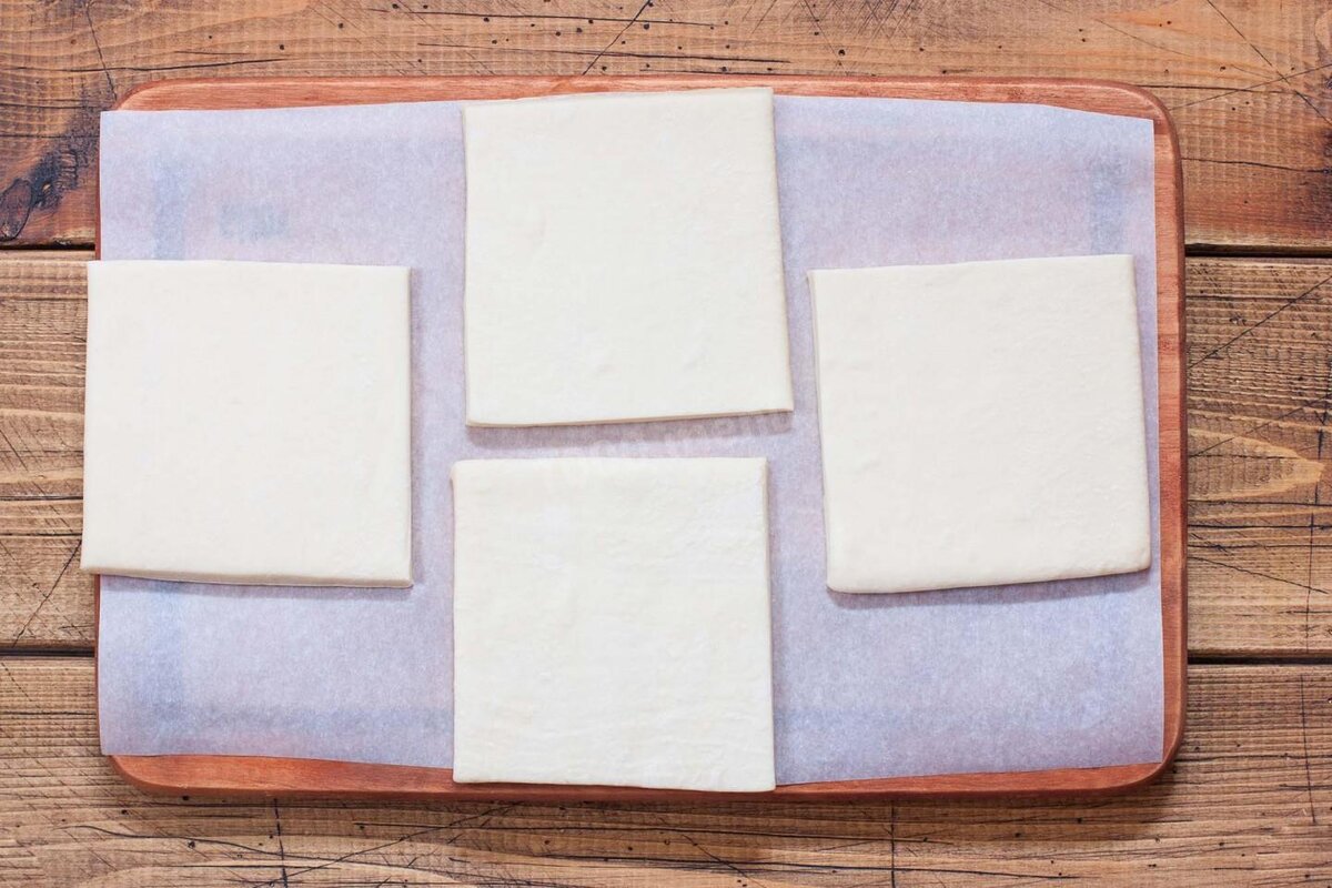 Слоёное тесто достаньте из упаковки, слегка разморозьте при комнатной температуре, затем отделите пласты друг от друга и оставьте ещё на 1.5 часа для окончательной разморозки. Размороженное тесто разделите на порционные кусочки. У меня тесто из двух пластин, каждую пластину я разрезала на четыре части. Включите разогреваться духовку до 180 градусов.