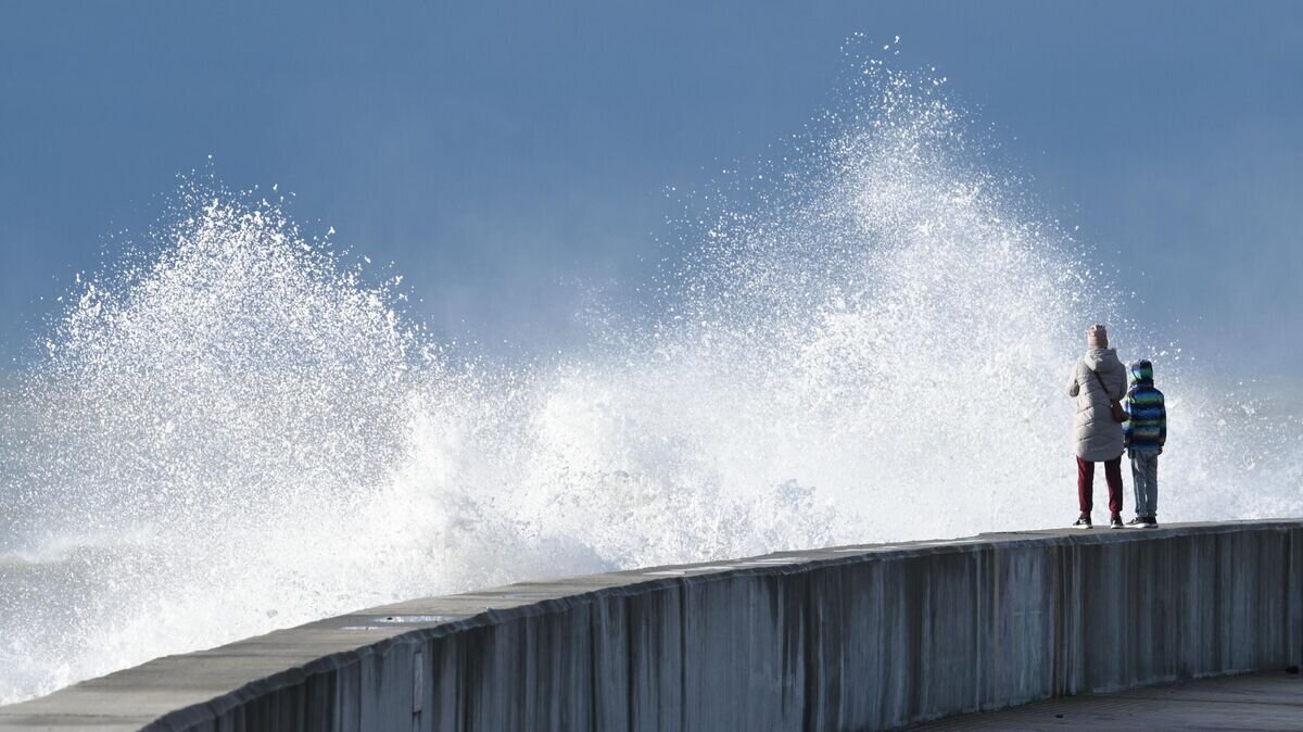    Прохожие на набережной в Адлере во время шторма© РИА Новости / Артур Лебедев