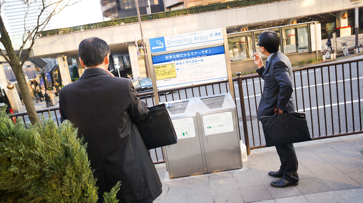 By Antonio Tajuelo - Fumar en Japón, CC BY 2.0, https://commons.wikimedia.org/w/index.php?curid=43097402. Офисный "планктон" курит в зоне для курения, Япония. 2013