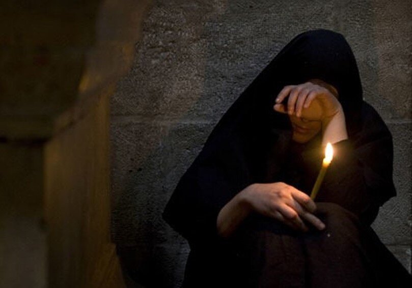 В городе траур висит тишина небо плачет. Девушка молится. Скорбящая женщина. Человек молится в храме.