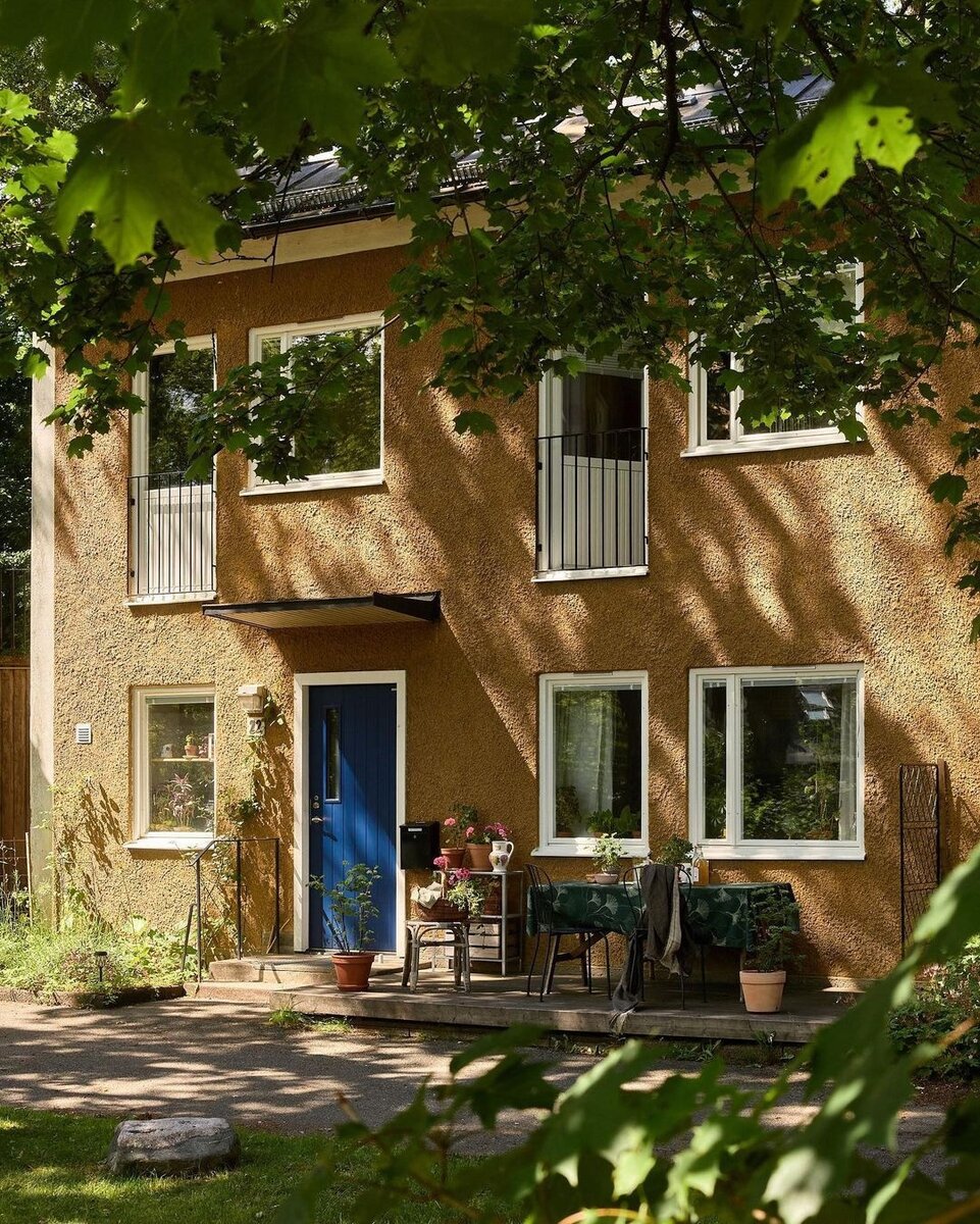 Начну с простого. Кажется, ничего необычного. Дом как дом, вместо шикарной террасы — стол с невзрачной скатертью, стул с цветами и пара растений в горшках. Но именно в этих простых деталях и кроется уют. У людей не было денег, но они все равно придумали, как при помощи подручных средств изменить свой двор