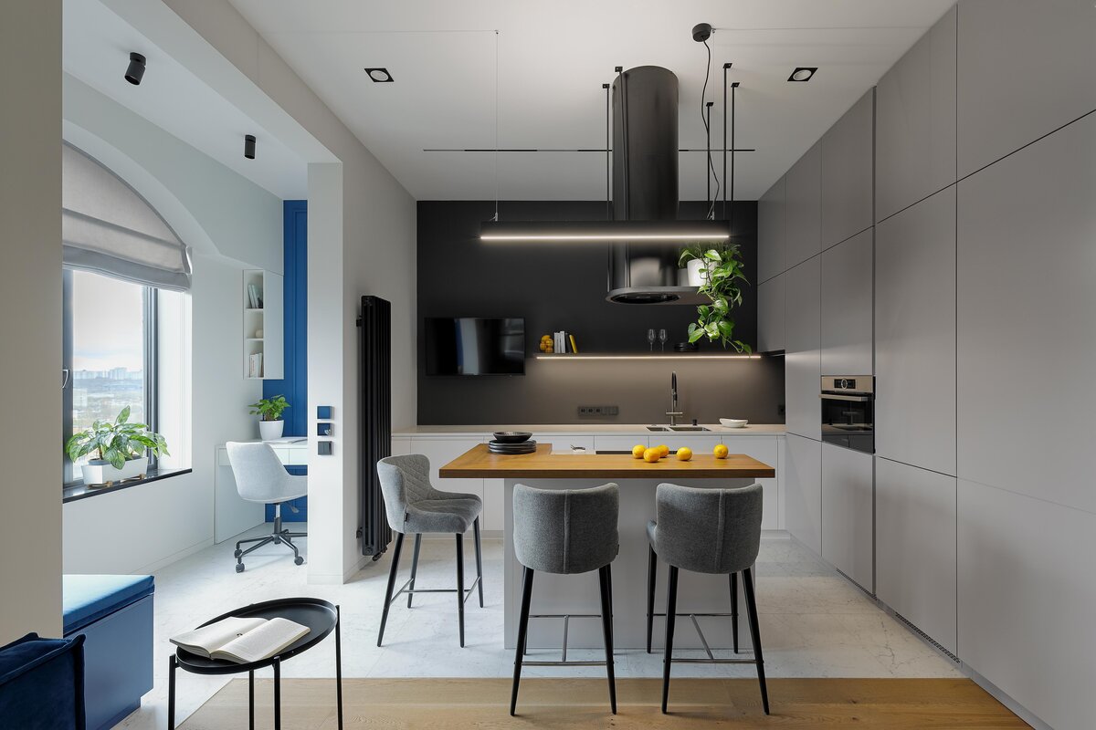    В результате перепланировки кухня превратилась в кухню-гостиную с компактной диванной зоной, большим гарнитуром, в котором организовано хранение, и кухонным островом с с тремя полубарными стульями., фото: Максим Максимов