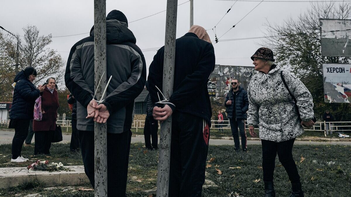    Жители Херсона, привязанные за руки к столбам на одной из улиц города© AP Photo / Libkos