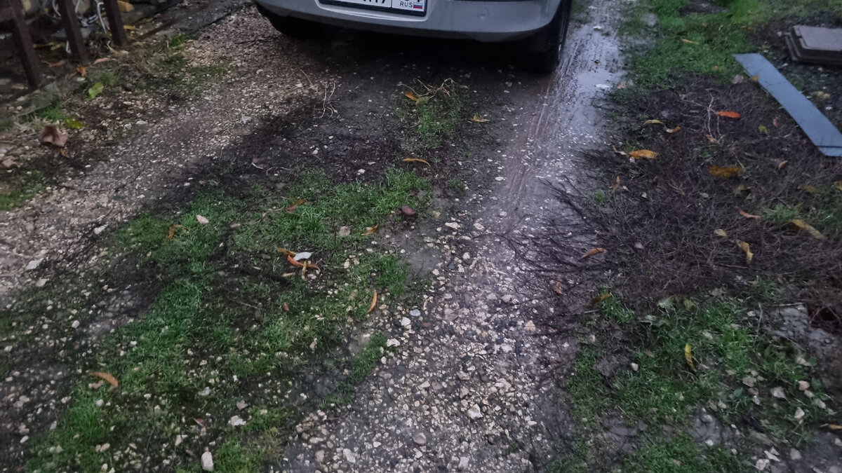 Это наша площадка, отсыпанная щебнем. На ней растут сорняки, летом они довольно высокие, раз в месяц нужно травить гербицидом. Периодически со щебня я собираю мусор вручную. В районе колёс щебень ушёл в землю и образовалась колея, в дождь здесь постоянно лужа и грязь.