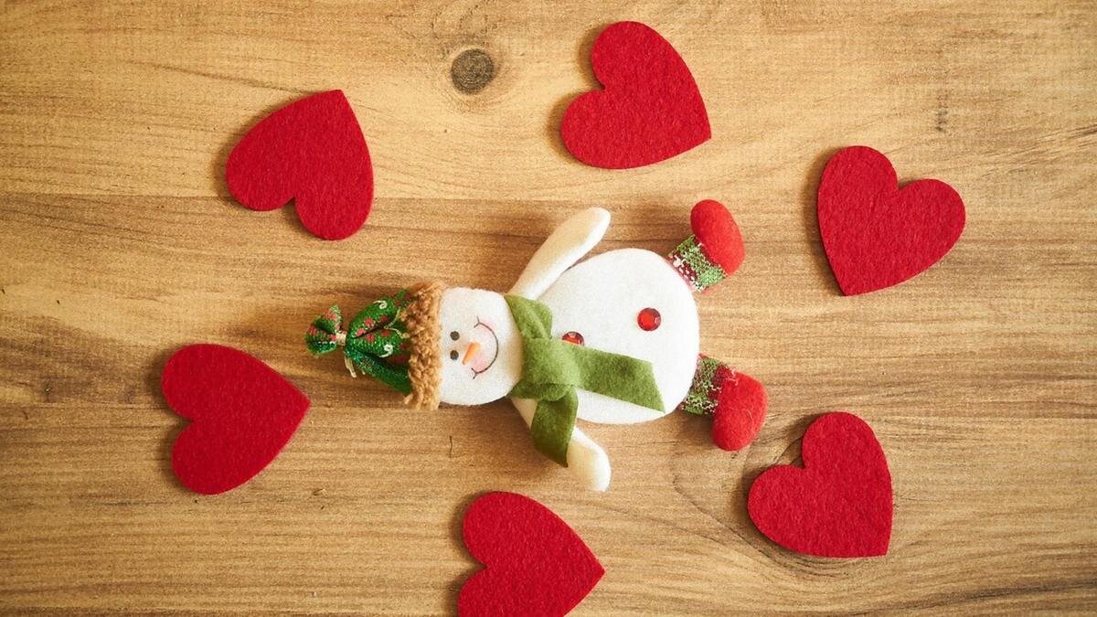    Снеговичок из фетра лежит на столе рядом с фетровыми красными сердечками:Pixabay