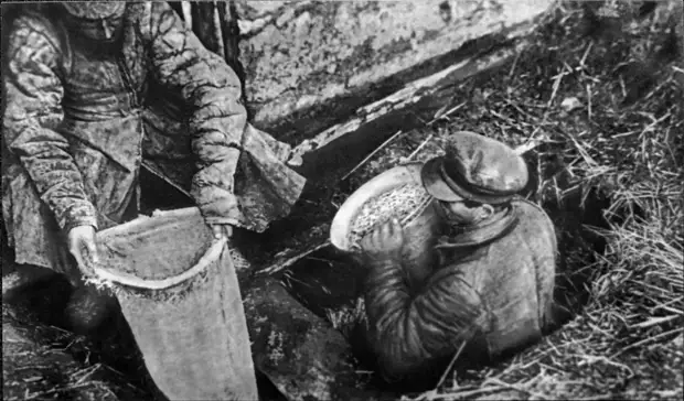 Работники ОГПУ извлекают из ямы спрятанное зерно. 1932 год. Фотография из Государственного музея политической истории России.