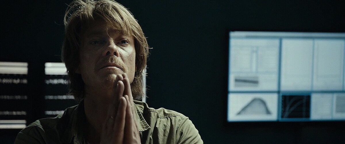 Главгерой наблюдает за показаниями компьютера, отслеживающего горную динамику.