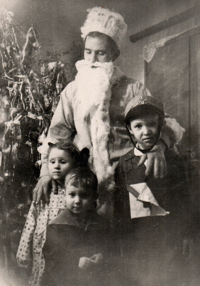 На фото само-собой я (в первом ряду, куда уж без меня), Людочка, соседский Славик, ну, и тот самый Дед Мороз. Он в отличии от многих – настоящий. У него, как и полагается, борода из ваты, и еще он был Людочкин папа и мой дядя Геннадий Макарович