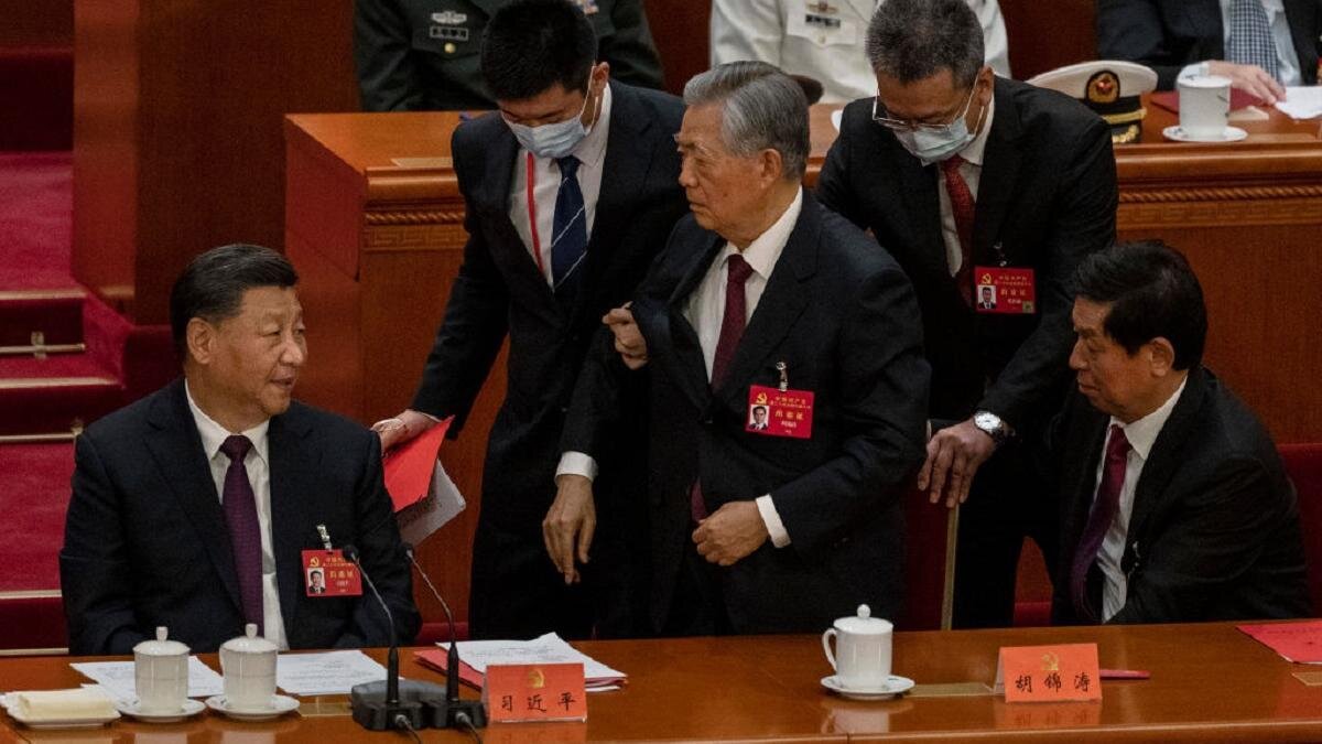    Двое людей в костюмах держат под руки Ху Цзиньтао:Kevin Frayer/Getty Images