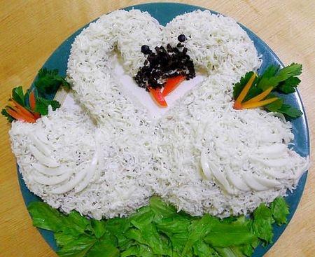 Салат "Лебединая верность" Ингредиенты: отварная куриная грудка - 1 шт, картофель - 3 шт, лук репчатый - 2 шт, шампиньоны - 300 г, яйца вареные - 5 шт, грецкие орехи - 200 г, сыр твердый - 200 г, майонез, для украшения - чернослив, черный перец горошком, красный болгарский перец, зелень.
Готовим: Картофель отвариваем, остужаем и натираем на терке. Мелкими кубиками нарезаем также отваренную куриную грудку. Порезанные соломкой грибы обжариваем с луком. Салат выкладываем слоями, промазывая майонезом. Из первого слоя формируем влажными руками лебедей. Вот порядок слоев: тертый картофель (на крупной терке), порезанная на мелкие кубики куриная грудка, грибы с луком, тертые на мелкой терке желтки, грецкие орехи измельченные, тертый сыр, тертые белки. Последний слой не смазывается майонезом. Салат оформляем зеленью, лебединые клювы делаем из красного болгарского перца и чернослива или маслин, а глаза - из черного перца горошком.
Приятного аппетита!