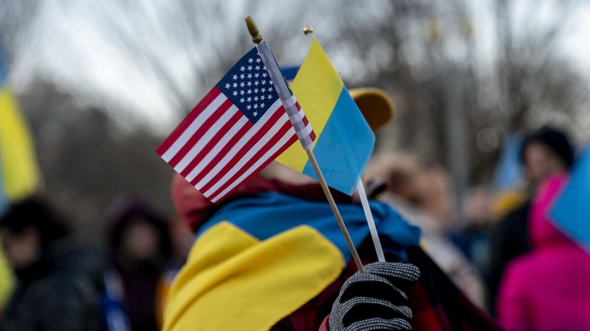 Человек держит флаги США и Украины перед Белым домом в Вашингтоне© AFP 2022 / Stefani Reynolds