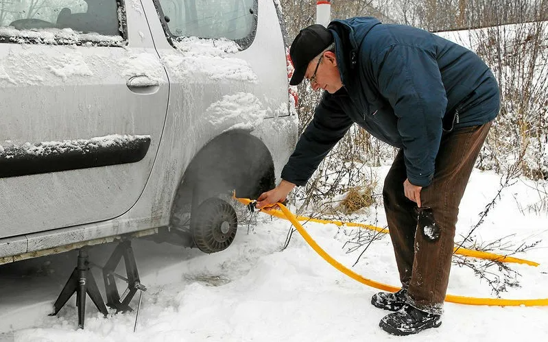Для того, чтобы избавиться от слоя льда, необходимо нагреть тормозной барабан, причем, если вы обладатель дисковых тормозов, то процедура будет несложной. 
Вероятность того, что вы найдете фен и розетку ничтожна мала, однако же его можно сделать из подручных предметов. Для этого вам понадобится шланг. Лучше всего приспособить для этого деталь от пылесоса. Один конец нужно закрепить на выхлопной трубе, а второй направить либо на суппорт, в случае с дисковыми колесами, либо на барабан. Дальше надо запустить ДВС и просто немного подождать.

Однако, найти шланг, который подойдет для этой работы, может быть довольно непросто. Некоторые советуют в подобном случае воспользоваться горячей водой. Но у этого способа есть и недостатки. При сильно минусе вы рискуете не только не растопить лед, но и создать еще один его слой.