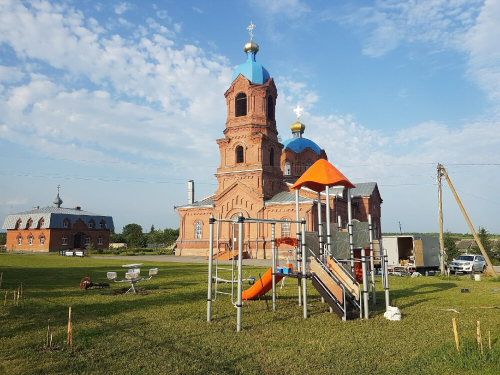    Каменный Никольский храм в селе Пушкари и детская площадка на переднем плане. Фото: Из личного архива/ Максим Насонов
