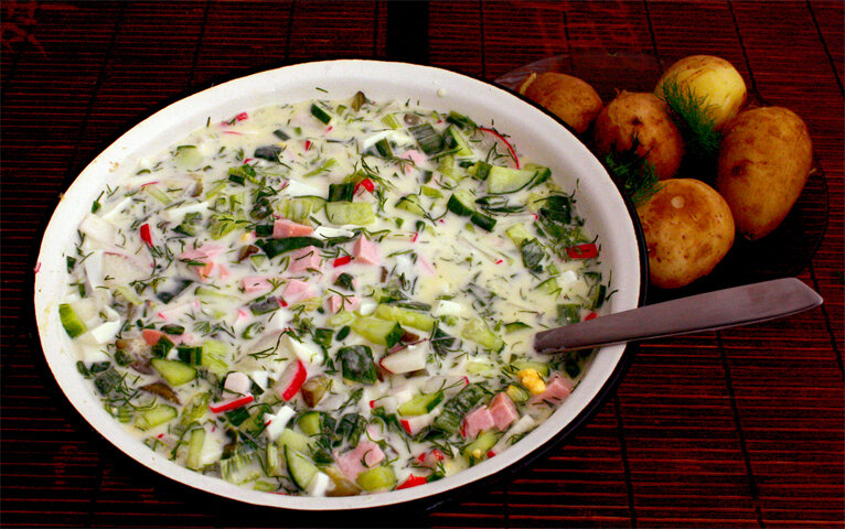  Освежает и прекрасно насыщает в знойное время года окрошка. Оригинальный вкус и простая технология сделало это блюдо любимым на многих столах. Возникло благодаря тому, что бережливые хозяйки соединили остатки пиршества и получили новый рецепт. За основу берется уже готовое мясо (свинина, говядина, мясо птицы), копчености, колбасы или рыба, свежие овощи – огурцы, редис, отварные картофель, морковь или репа, соленые огурцы, грибы. Составляющие нарезают небольшими кубиками и заправляют несладким хлебным квасом (возможны варианты сывороткой или кефиром). Для рыбной окрошки подходят те сорта, которые имеют нейтральный вкус и не имеют мелких костей. Квас предварительно охлаждают, чтобы все ингредиенты сохранили свойства, и не разрушилась консистенция. Украшать это блюдо принято зеленым луком и укропом.