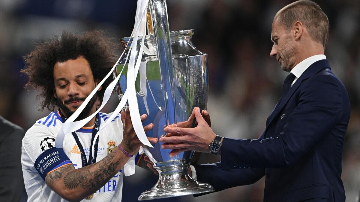    Президент Союза европейских футбольных ассоциаций (УЕФА) Александер Чеферин вручает кубок турнира Лиги чемпионов по футболу сезона 2021/22 игроку "Реала" Марсело© РИА Новости / Алексей Филиппов