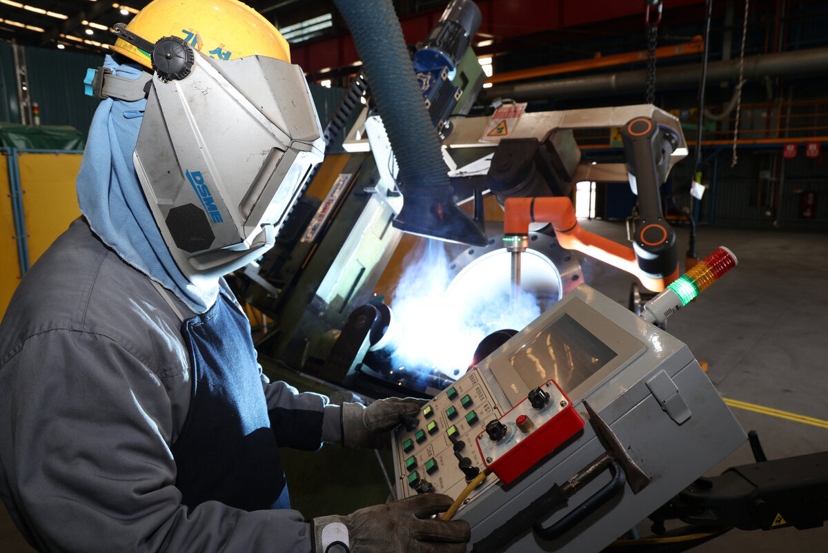 Рабочие  работают со сварочными роботами, разработанными Daewoo Shipbuilding  & Marine Engineering [Предоставлено Daewoo Shipbuilding & Marine  Engineering]