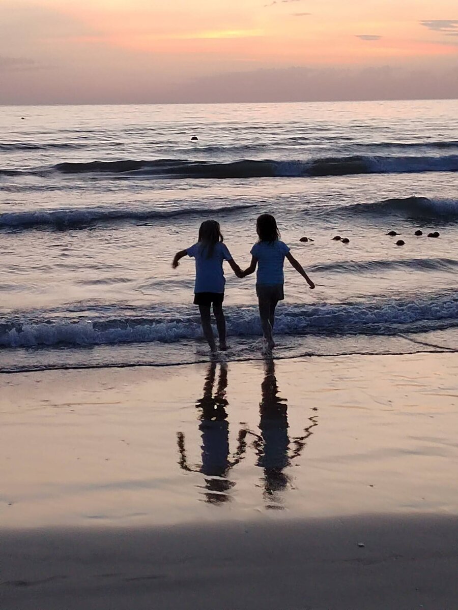 Девочки-близнецы играют на берегу Черного моря во время вечернего купания. Из личного фотоальбома.