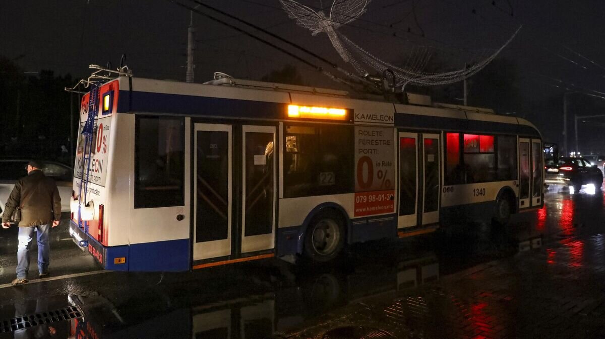    Мужчина проходит мимо троллейбуса, остановившегося из-за отключения света в Кишиневе© AP Photo / Aurel Obreja
