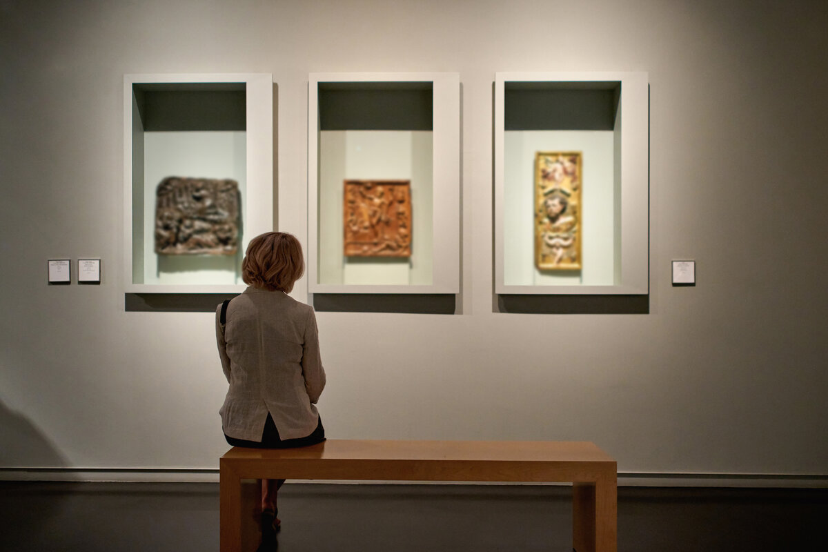 "Woman stading in a room looking and pointing at the empty frames displayed"                  Автор: JENOCHE