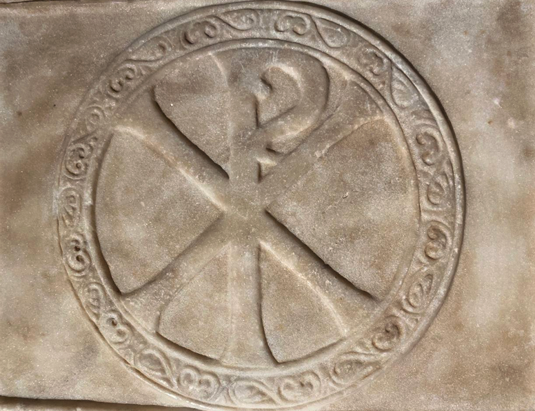 Знак хрисмы на крышке реликвария в собрании Музея Христианской культуры (Византия, предп. VI в.). Камень, резьба.