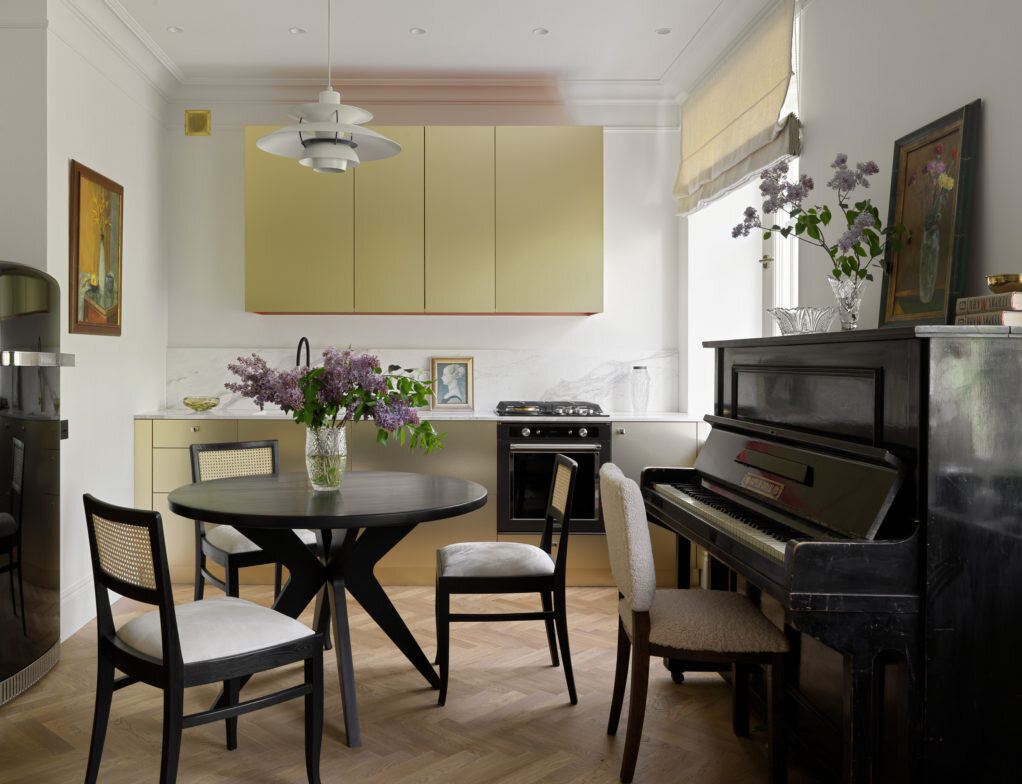 Гостиная. Стол, ручная работа мастера Антона Лакшмана; кухня с эффектом чеканки сделана на заказ в Риге компанией Bosco Studio, за золотыми фасадами скрываются красные шкафчики; винтажная люстра, бутик Евгении Кудрявцевой; холодильник, плита, духовка, Kitchen Aid; стулья отреставрированы и переобиты, студия реставрации (Rest)Art; мойка в кухне, Blanco; мрамор (подоконники, столешница, фартук на кухне), Royal Stone; окна, Futura; паркет, “Фаворит”. Живопись прадедушки Насти Александра Курского, багетные рамы Настя подобрала в AG-Studio.