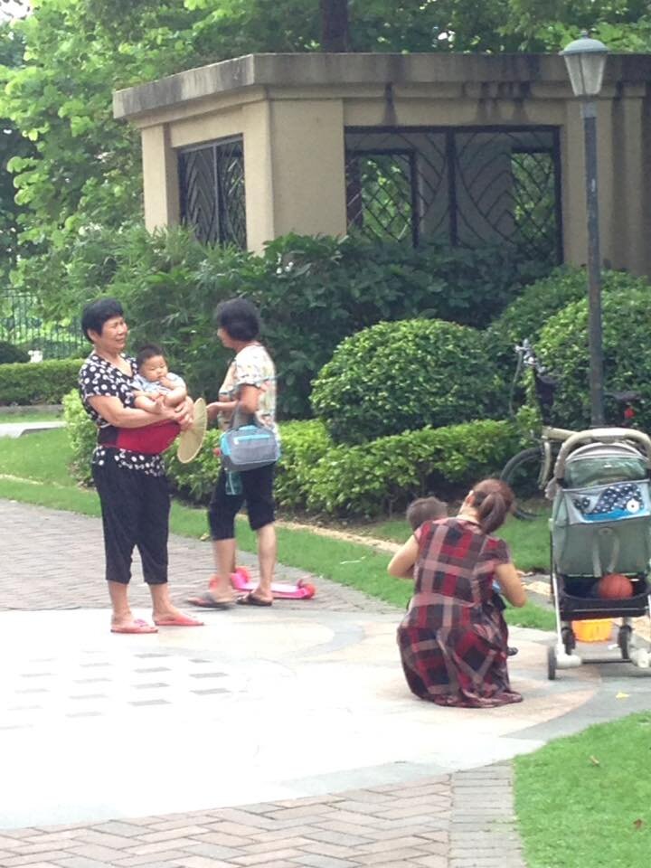 На китайской бабушке надет специальный пояс с подставкой для малыша