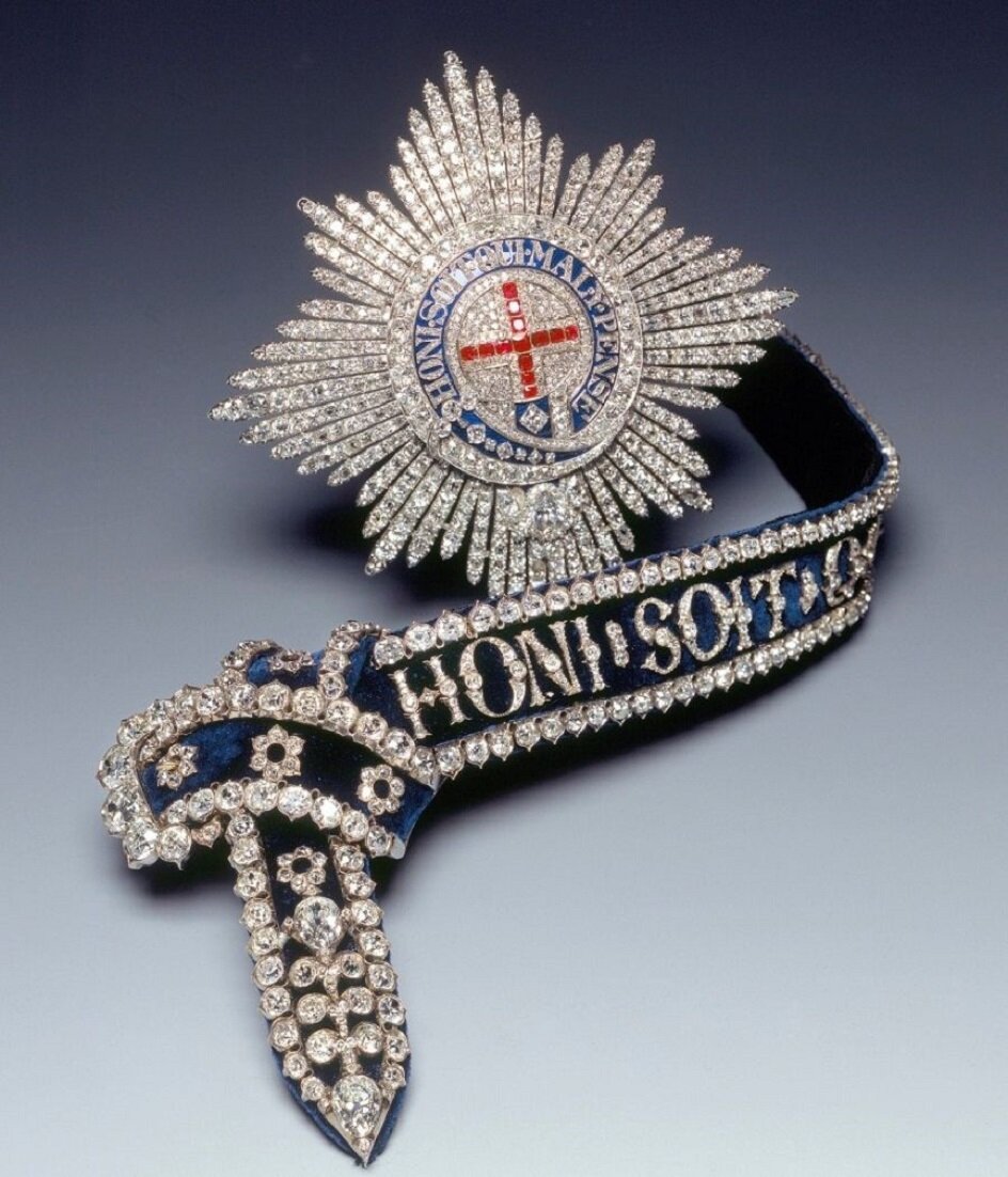 Звезда Ордена Подвязки, инкрустированная бриллиантами и рубинами, и сама подвязка - тёмно-синяя бархатная лента с надписью "Да стыдится тот, кто подумает об этом дурно"