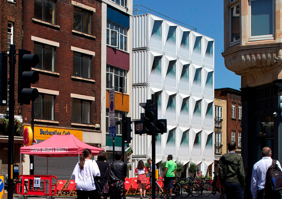 Вид на дом из контейнеров среди других, более традиционных домов