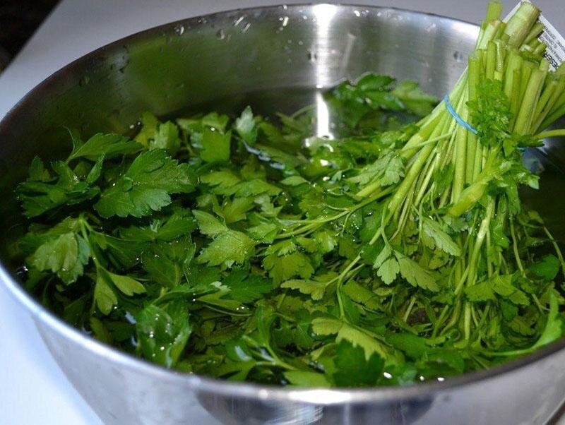 Первым делом петрушку кладут в просторную миску. Заливают водой и оставляют на 5 минут. За это время остатки почвы опустятся на дно посуды. Затем зелень промывают под краном, стряхивают и дают немного просохнуть. Режут мелкими кусочками.