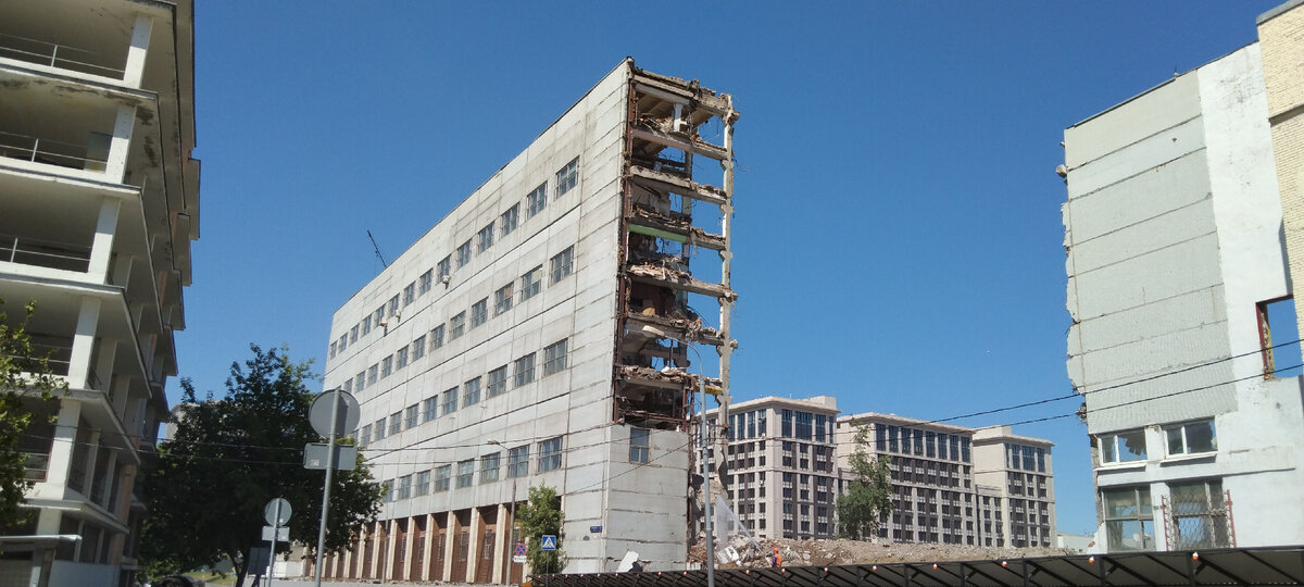 Экскаватор по кусочкам разбирает старые здания.