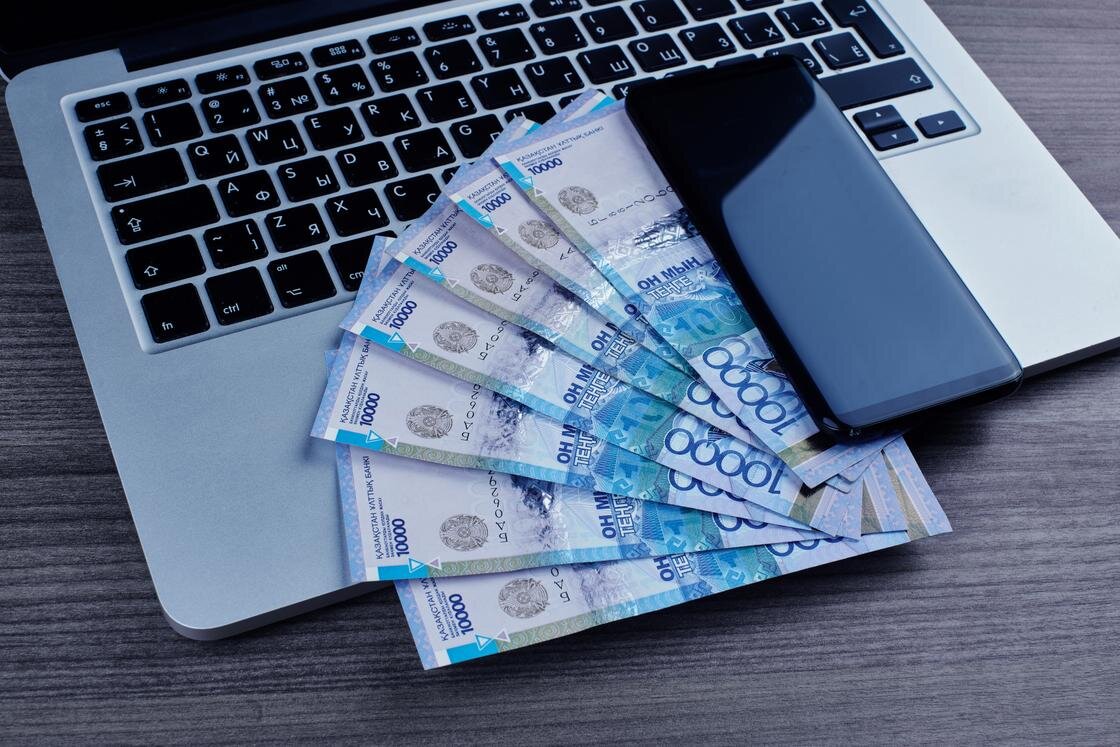    Деньги лежат на ноутбуке рядом с телефоном:amixstudio/Getty Images